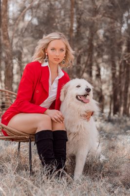 Dog posing with a woman in a short red dress
